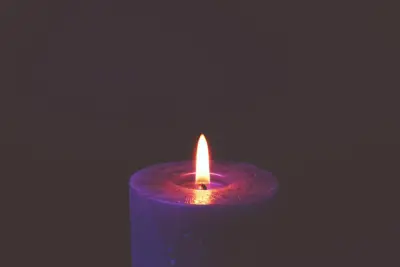 A single lit candle glowing in a dim room