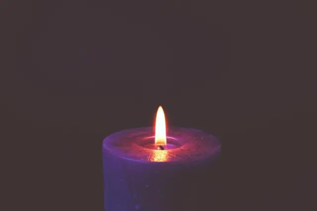 A single lit candle glowing in a dim room