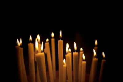 Rows of thin candles burning in the dark