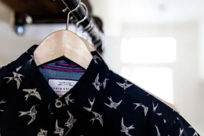 A dark patterned shirt hanging on a wooden hanger