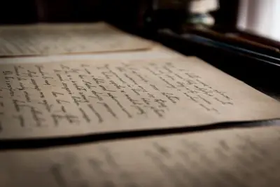 Old handwritten pages lying open on a table in soft light