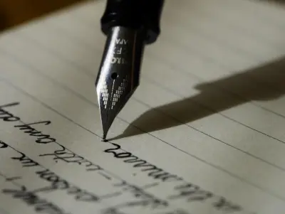 Close-up of a fountain pen nib writing cursive on lined paper