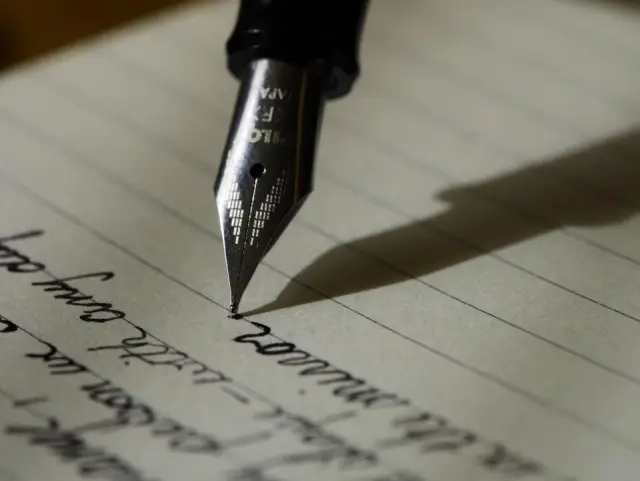 Close-up of a fountain pen nib writing cursive on lined paper